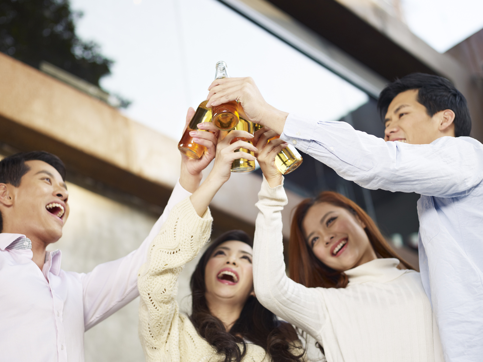 young friends raising beer bottle for a toast